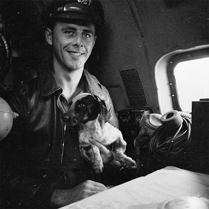WHI Image ID 99893 Lieutenant Paul Seramur of Milwaukee, Wisconsin, at the navigator table in a Consolidated B-24 Liberator warplane during the Alexishafen strike. He is holding his pup, Cobber. Alexishafen was a Japanese occupied airbase located on the northeast coast of New Guinea (present day Papua New Guinea), near Madang